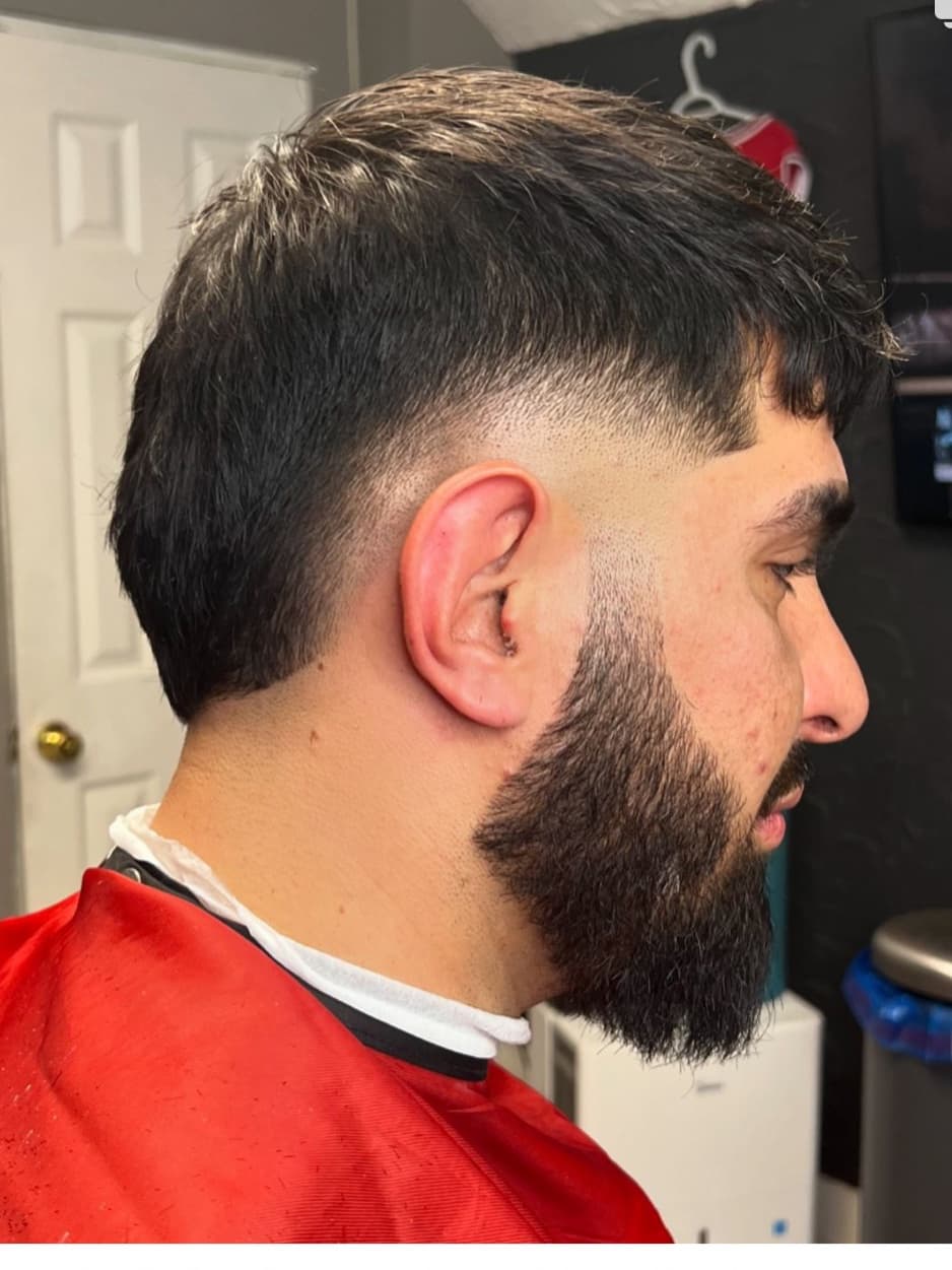 Burst fade arcing around the ear, textured on top, with a full shaped beard