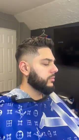 Finished low fade with a full beard, side profile